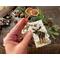 A natural gift tag with a moose wood-burned onto the bark. Tag has a rustic cord tied to a hole in the top corner. 